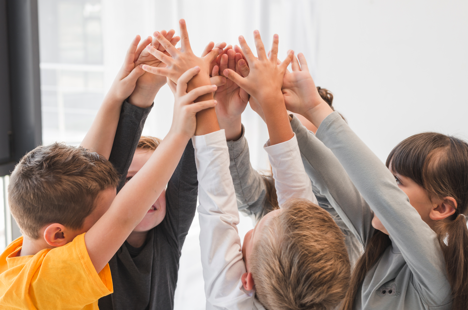 Groupe d'enfants les mains levés qui s'amusent ensemble.