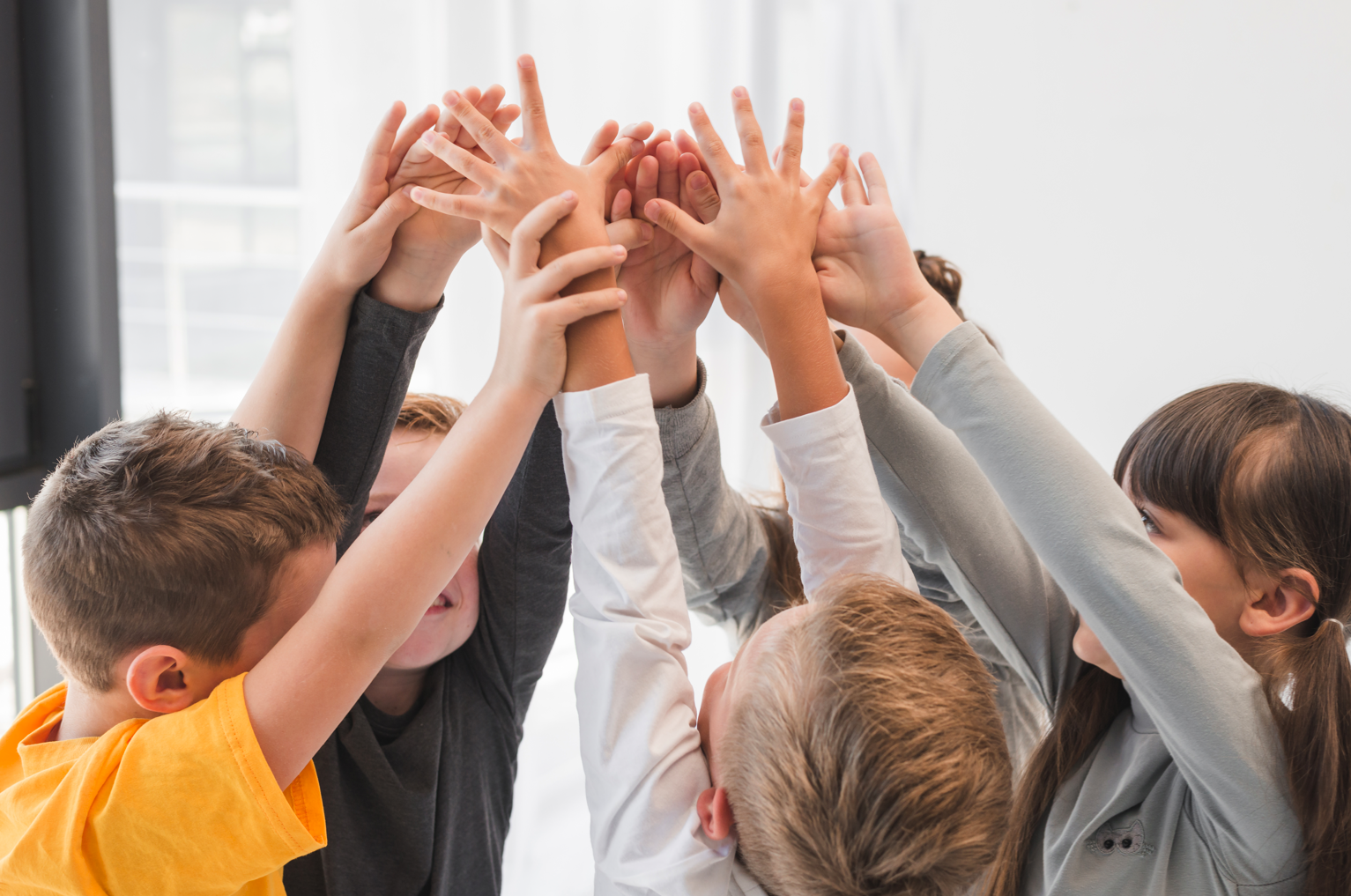 Groupe d'enfants les mains levés qui s'amusent ensemble. 